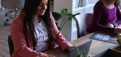 Two women working at laptops in a stylish office space, focused and productive.