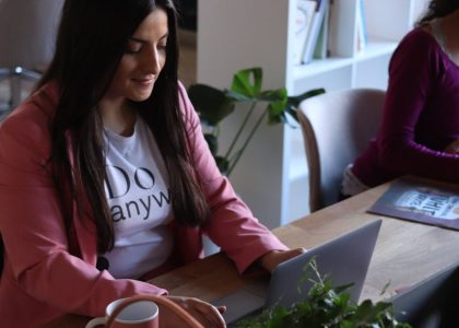 Two women working at laptops in a stylish office space, focused and productive.